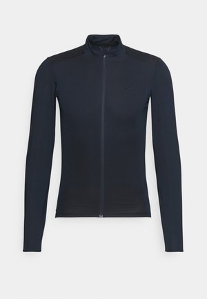 Chaqueta negra ajustada de manga larga con cremallera frontal completa y cuello alto, mostrada sobre un fondo gris claro.