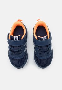 Para granatowych sneakersów dla dzieci z pomarańczowym wykończeniem wewnętrznym, wykonanych z siateczkowego materiału, z rzepami, ułożonych obok siebie na białym tle.