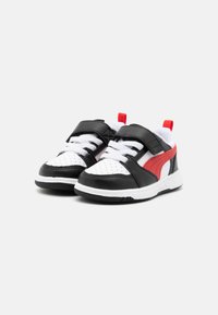 Baskets noir et blanc avec des accents rouges, dotées d'un bout perforé, de brides réglables et de semelles en caoutchouc texturé. Convient aux enfants.