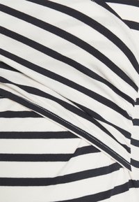 Randig tyg med vita och mörkblå horisontella ränder, med en mjuk textur och synlig söm längs kanterna.