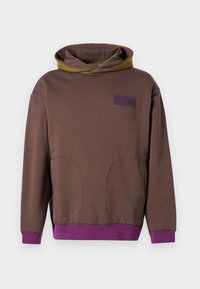 Felpa marrone con cappuccio in contrasto verde oliva, accenti viola sui polsini e sull'orlo, e due grandi tasche frontali. Materiale: tessuto morbido.