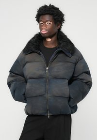 Puffer jacket in dark blue with a faux fur collar, zip closure, and padded sections; features a smooth texture and subtle pattern.