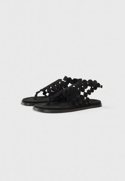 Svarta sandaler med övre i mocka, med ett rundat snitt-design och en platt sula. Öppen tå-stil med en mellan-tån rem.