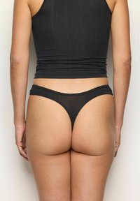 Set de top din bumbac negru cu dungi și thong, având un design ajustat, textură subtilă și un stil minimalist, văzut din spate.