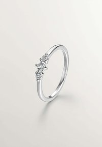 Anillo de plata con tres piedras preciosas transparentes alineadas en la parte superior, con una banda suave y delgada y un acabado pulido.