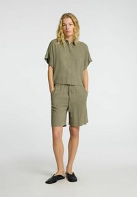 Olive green two-piece set featuring a short-sleeve button-up shirt and drawstring waist shorts. Soft fabric with a relaxed fit and pockets.