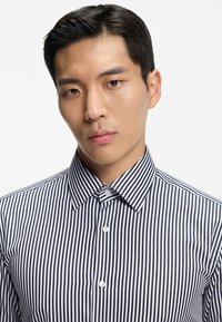 Marineblauw-wit gestreept shirt met een puntkraag en knoopsluiting aan de voorkant, met een gladde stoftextuur en nauwkeurige, smalle strepen.