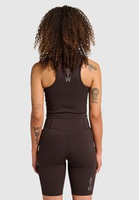 Brun sports tanktop og høj talje shorts lavet af strækstof. Har logo på ryggen og låret. Glat tekstur, tætsiddende design.