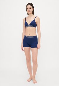 Navyblåt underklädesset som innehåller en bralette med tunna axelremmar och en matchande boxershorts, båda med vit logobanddetalj.