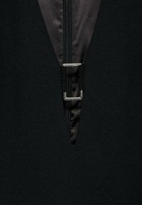 Svart zip-up-plagg med en triangelmönsterdetalj, metalldragkedja och textil med en slät innervärld.