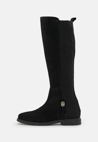 Bottes noires montantes jusqu'aux genoux en daim avec un panneau en tissu côtelé, semelle plate et un accent doré sur le côté. Conception à bout arrondi.