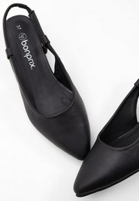 Pantofole slingback nere in sintetico con punta a punta. Texture liscia, design minimalista, caratterizzata dal logo "bonprix" sulla soletta interna. Taglia 37.