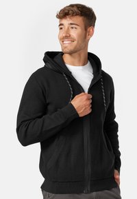 Black zip-up hoodie with a drawstring hood, two front pockets, ribbed cuffs and hem, featuring a textured fabric for warmth.