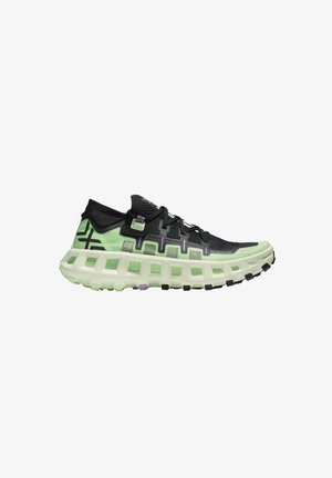 Zapatilla deportiva negra y verde con suela acolchada y gruesa que presenta recortes rectangulares y cordones negros sobre fondo blanco.