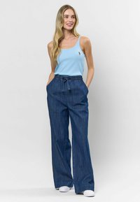 Un top sans sans mâne bleu deschis și o pereche de pantaloni fără formă din denim albastru închis, cu un cordon la brâu. Outfitul are un design simplu și casual.