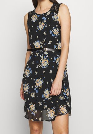Robe noire sans manches avec imprimé floral jaune et bleu, détail en dentelle à l'épaule et ceinture noire fine à la taille.