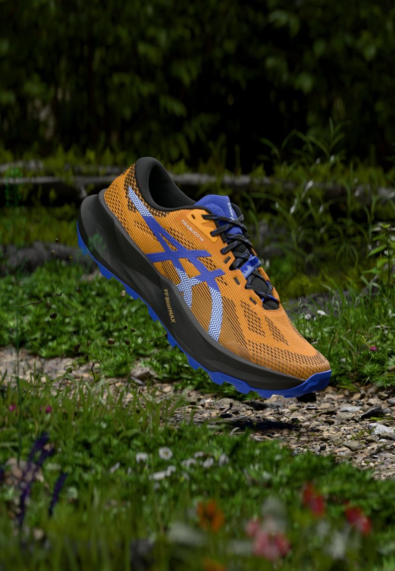 Chaussure de course en maille orange avec des accents noirs et une semelle bleue. Présente un motif en zigzag blanc et un logo sur le côté. Légère et texturée.