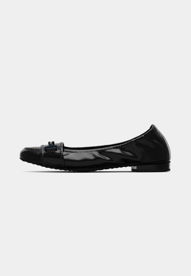 Chaussure plate en cuir verni noir avec un petit talon et un détail de boucle décoratif à l'avant, montrée en profil latéral sur un fond uni.