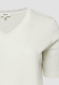 Haut blanc à manches courtes pour femmes avec col en V orné de dentelle, texture en tissu côtelé et étiquette de la marque s.Oliver à l'intérieur du col.