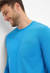 Langarmshirt van felblauwe stof met een gestructureerde afwerking, voorzien van een borstzak en ronde hals.