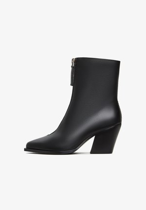Czarne skórzane botki za kostkę z ostro zakończonym noskiem, bocznym zamkiem błyskawicznym i średnim obcasem w kształcie bloku. Gładka tekstura z minimalnymi detalami.