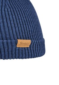 Navy blue ribbed knit beanie hat with a folded cuff and a small tan leather label featuring scripted text.