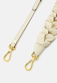 Vit läderrem med en flätad design, med guldfärgad metallhardware och clips i båda ändar för fäste. Slät textur och söm.