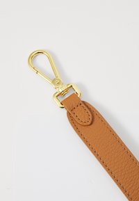 Cinturino in pelle color crema con finitura testurizzata, dotato di una chiusura e connettore in metallo dorato. Dettagli cuciti lungo il bordo.