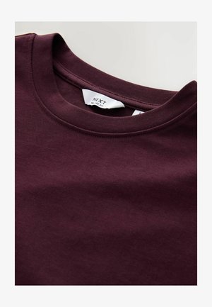 Bordeauxrote Baumwoll-T-Shirt mit Rundhalsausschnitt und lässiger Passform. Es hat eine glatte Oberfläche und ein Etikett mit der Marke "NEXT."