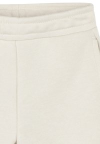 Pantaloni sportivi di un beige chiaro con vita a coste, tessuto morbido e funzionale con tasche laterali.