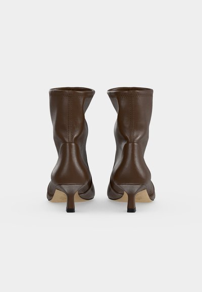 Paire de bottines en cuir marron avec petits talons bas type kitten, vues de dos sur fond blanc uni.