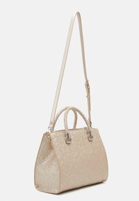 Sac à main beige avec une surface texturée, présentant un motif géométrique, des poignées tressées et une bandoulière réglable. Accents en matériel argenté.