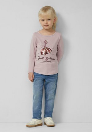 Lichtroze langemouwen shirt met een ballerina-graphic, versierd met pailletten, gecombineerd met blauwe jeans en witte sneakers.