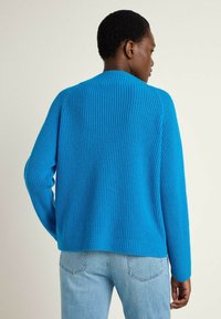 Blauer gerippter Pullover mit rundem Ausschnitt, langen Ärmeln und lockerer Passform. Die Textur ist weich und die Farbe ist einfarbig ohne Muster.