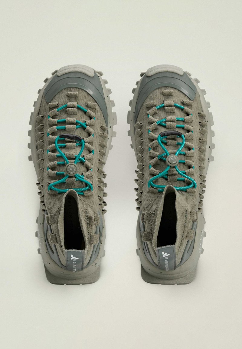 Grijze buitenschoenen met een structuurstof bovenkant, rubberen accenten en turquoise veters. Heeft een robuuste zool voor grip en ondersteuning.