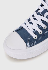 Sneaker in tela blu con punta in gomma bianca, lacci bianchi e occhielli argentati. Presenta cuciture a contrasto e suola testurizzata.