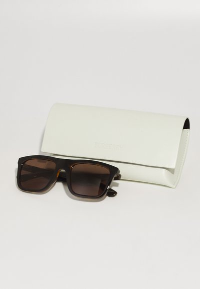 Burberry sunglasses with a dark tortoiseshell frame and brown lenses, accompanied by a soft white leather case embossed with the brand name.