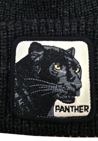 Cappello di maglia nera con un patch ricamato di una testa di pantera con occhi gialli, su uno sfondo bianco, e etichettato "PANTHERA".