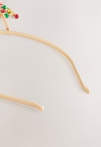 Haarring in goudkleur met een decoratief, kleurrijk kraalelement dat lijkt op een kerstboom. Heeft een glad, gebogen ontwerp en een dun, flexibel frame.