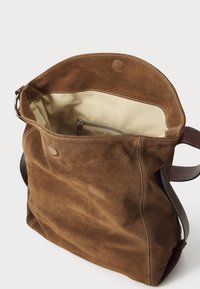 Bruine suède tote bag met een tan kleurige binnenkant, voorzien van een ritsvak aan de binnenzijde en duurzame leren handvatten. Stiksel details op de randen.