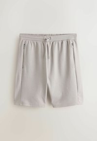 Shorts décontractés gris clair avec taille à cordon et deux poches zippées verticales sur les côtés avant, posés à plat sur un fond blanc.