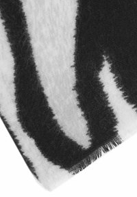 Wool blend blanket featuring a black and white abstract pattern with fringe edges, soft texture, and a rectangular shape.