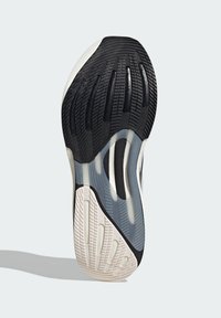 Semelle de chaussure au design multicouche. Principalement noire avec des accents blancs, présentant des motifs texturés pour l'adhérence et la flexibilité.