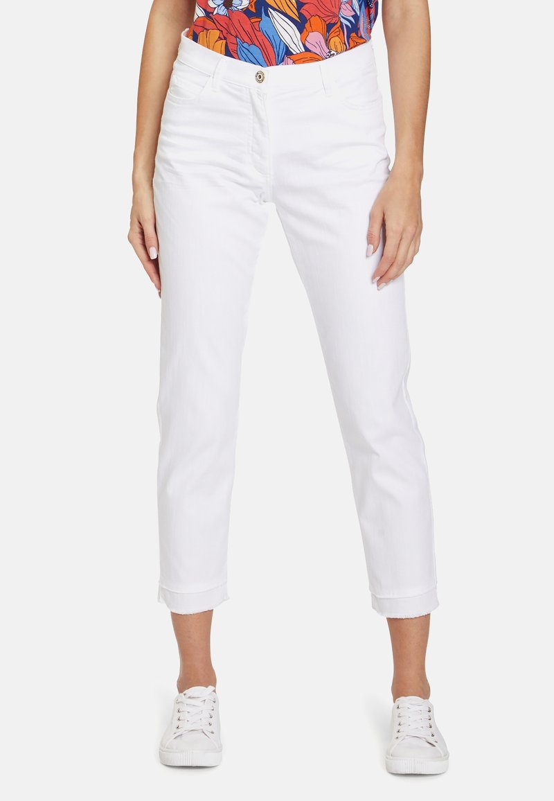 Vita bomullsjogg med rak skärning, uppvikt fåll och knappstängning fram. Tillsammans med en färgglad blommig topp och vita sneakers.