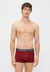 Boxer briefs in cotone bordeaux con una vita elastica nera decorata dal logo "GUESS", design aderente e texture liscia.