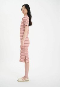 Robe midi rayée en coton rouge et blanc, avec un col, des manches courtes et des fentes sur les côtés pour plus de liberté de mouvement.
