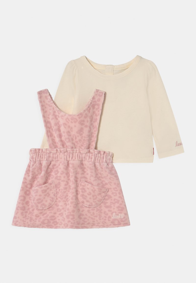 Tvådelad barnoutfit: en ljus beige långärmad topp och en rosa leo-printade kordflöjdsklänning med fickor och elastisk midja.