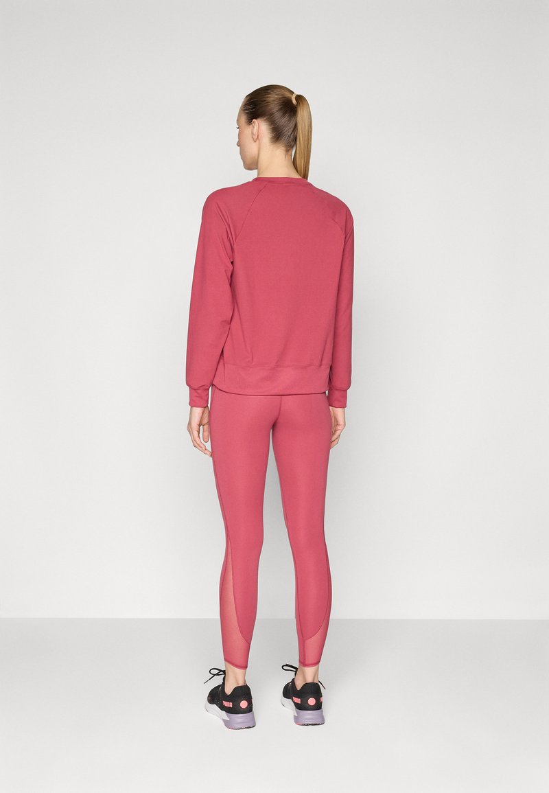 Yoga-Set bestehend aus einem bordeauxfarbenen Sweatshirt und passenden Leggings mit Netzpaneelen. Das Outfit besteht aus einem dehnbaren, atmungsaktiven Material.