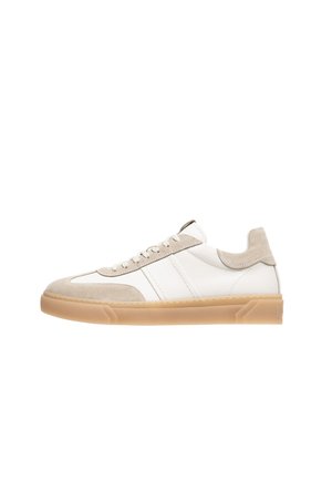 Zapatillas de cuero blancas con acentos de ante beige, punta redondeada, parte delantera con cordones y suela de goma texturizada. Presenta rayas horizontales blancas.