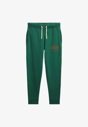 Zielone dresowe spodnie z elastycznym pasem, sznurkiem, dwoma bocznymi kieszeniami i ściągaczami na kostkach. Na przodzie znajduje się logo w kolorze pomarańczowym.
